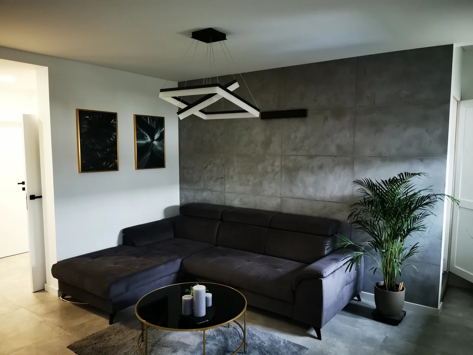 Wykończony salon z dekoracyjną szarą ścianą, drewnianą podłogą i oświetleniem