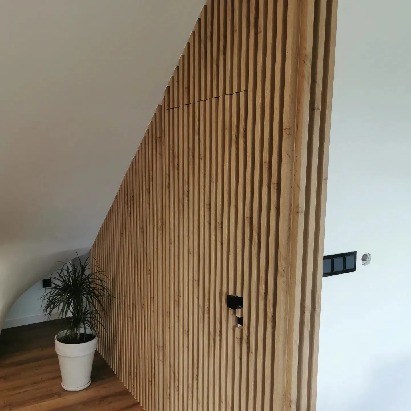 Drewniane lamele na ścianie salonu dopasowane do skosu